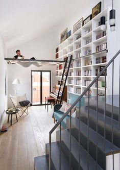 a man sitting on top of a stair case next to a book shelf filled with books