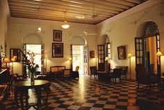 a large room with black and white checkerboard flooring, chandeliers and pictures on the walls