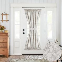 a white door with curtains hanging from it's side and a rug on the floor