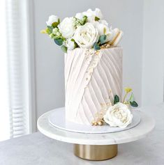 there is a white cake with flowers on the top and gold trimmings around it