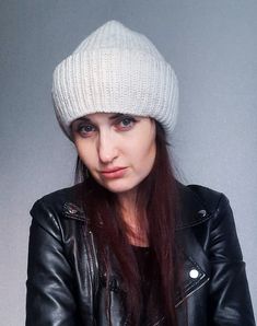 a woman with long red hair wearing a white knitted hat and black leather jacket