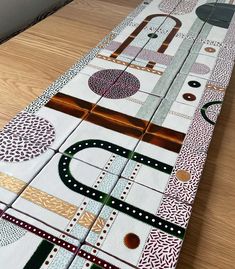 a table runner made out of fabric with circles and dots on it, sitting on a wooden floor