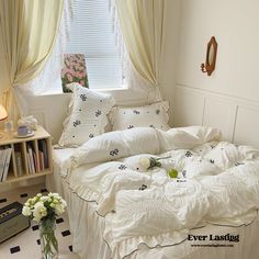 a white bed sitting next to a window in a room with curtains on the windowsill