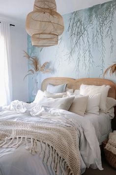 a bed with white linens and pillows in a room decorated with wicker lamps