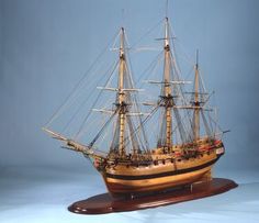 a wooden model of a sailing ship on a blue background with the sails still down