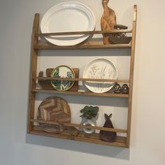 a wooden shelf with plates and other items on it, against a white wall in a room