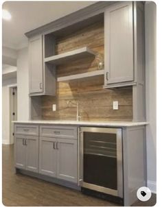 an empty kitchen with gray cabinets and wood flooring in the middle of the room