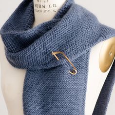 a blue knit scarf with gold buttons on the end and a white mannequin torso