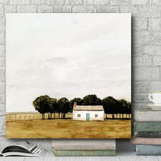 an open book sitting on top of a table next to a white brick wall with a painting