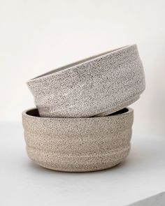 two gray bowls sitting on top of a white counter next to each other in front of a white wall