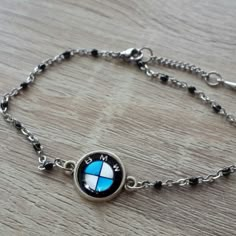 a silver bracelet with a blue and white bmw emblem on the front, sitting on a wooden surface