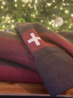 two red and black pillows sitting on top of a wooden table next to a christmas tree