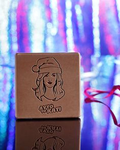 a close up of a chocolate box with a woman's face on it and a red ribbon in the background