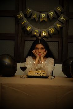 a woman sitting in front of a birthday cake