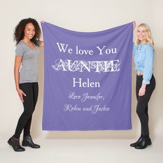 two women holding up a purple banner with the words we love you annie and helen