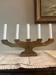 a candelabra with five candles on it in front of a framed painting