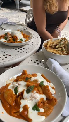 a woman sitting at a table with two plates of food