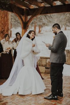 the bride and groom are exchanging vows at their outdoor wedding ceremony in winter time, surrounded by other guests