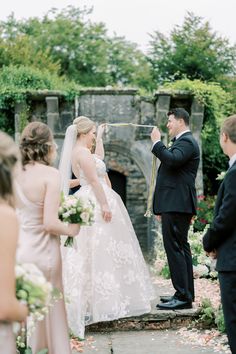 a bride and groom standing in front of an outdoor fire place during their wedding ceremony