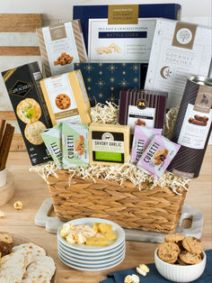 a basket filled with cookies and crackers next to other snacks on a wooden table