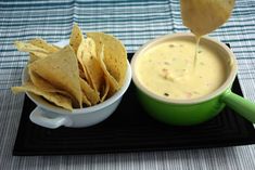 tortilla chips and dip in a green bowl on a black tray