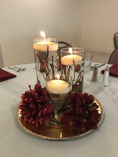 three candles are lit on a plate with flowers