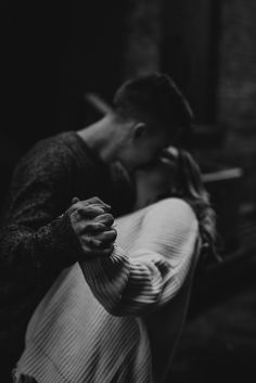 black and white photograph of a man kissing a woman's face in the dark