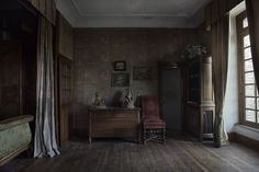 an old fashioned bedroom with wooden floors and wallpaper, including a chair in the corner