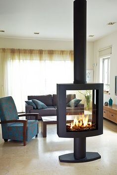 a living room filled with furniture and a fire place in the middle of the floor