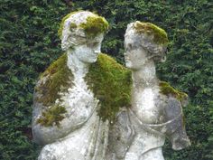 two white statues with moss growing on them