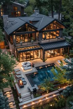 an aerial view of a large house in the woods at night with outdoor furniture and lighting