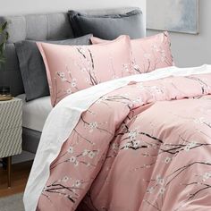 a bed with pink comforter and pillows on it