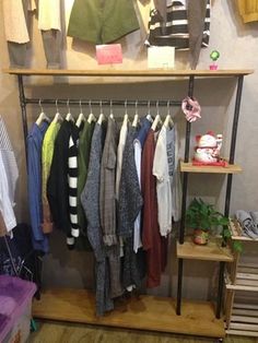 a rack with clothes hanging on it in front of a wall mounted shelf filled with clothing