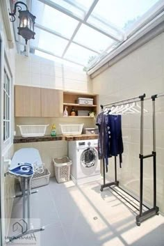 a washer and dryer sitting in a room next to a laundry basket with clothes hanging on it