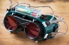 a pair of green binoculars sitting on top of a wooden table with wires attached to it