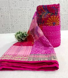 a pink and purple blanket with a small green plant on top