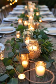 a long table is set with candles and greenery for an outdoor dinner or party