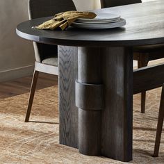 a wooden table with plates and silverware on it in front of a beige area rug