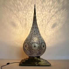 a lamp that is sitting on top of a wooden stand with a light shining through it