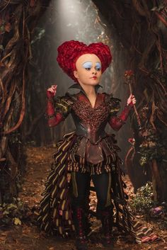 a woman with red hair and blue eyes standing in the woods wearing a costume made out of feathers