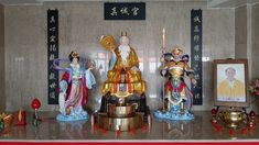 a group of statues sitting on top of a table next to pictures and vases