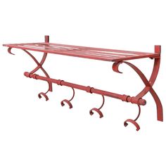 a red metal shelf with four hooks on it