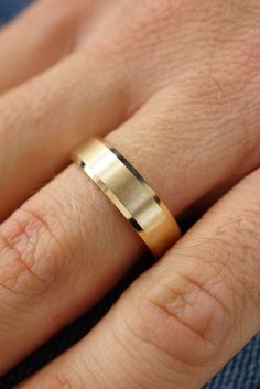 a close up of a person's hand with a gold ring on their finger