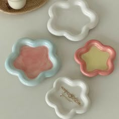 three ceramic dishes sitting on top of a white table next to a cup and saucer