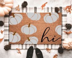 a door mat with pumpkins and pine cones on it, next to black shoes