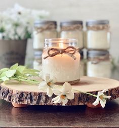 a candle sitting on top of a piece of wood next to some flowers and candles