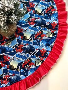 a red and blue table cloth with spiderman images on it, sitting next to a potted plant