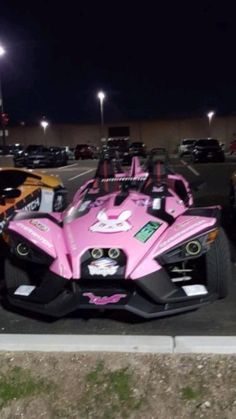 two pink cars parked in a parking lot next to each other on the side of the road