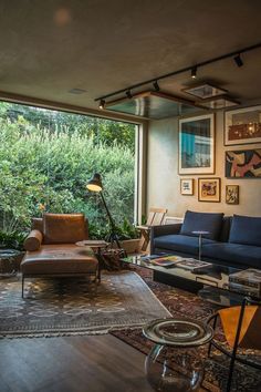 a living room filled with furniture next to a large glass window covered in greenery