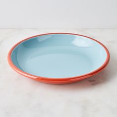 an orange and blue bowl sitting on top of a white counter